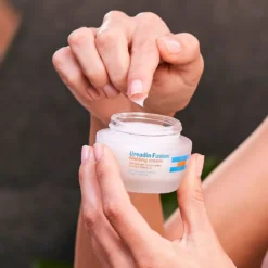 Une personne prélève de la crème ISDIN Ureadin Fusion Melting Cream à l’aide de ses doigts.