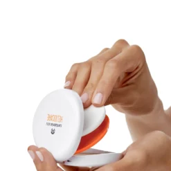 Ouverture du compact solaire Heliocare avec une main pour application.