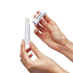 Baume à lèvres Hydraction de Sensilis ouvert, tenu par une main