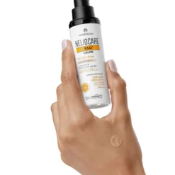 Flacon de gel solaire teinté Heliocare 360 Color Oil-Free Beige SPF 50+ tenu en main, prêt pour application.