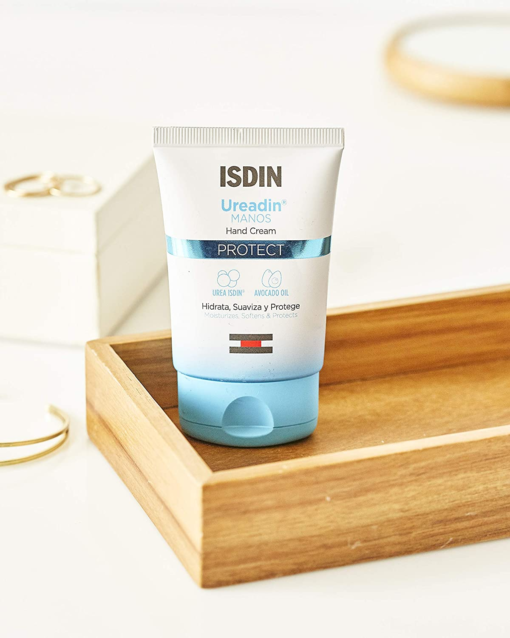 Crème ISDIN Ureadin Manos Protect posée sur un plateau en bois.