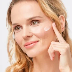 Femme appliquant la crème ISDIN A.G.E. Reverse Day sur son visage.