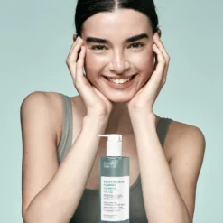 Femme souriante tenant le gel nettoyant Purify Essential Sensilis