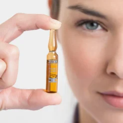 Gros plan d’une ampoule ISDIN Pigment Expert tenue entre les doigts.