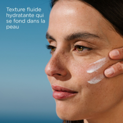 Femme avec une texture fluide de crème solaire hydratante sur la joue.