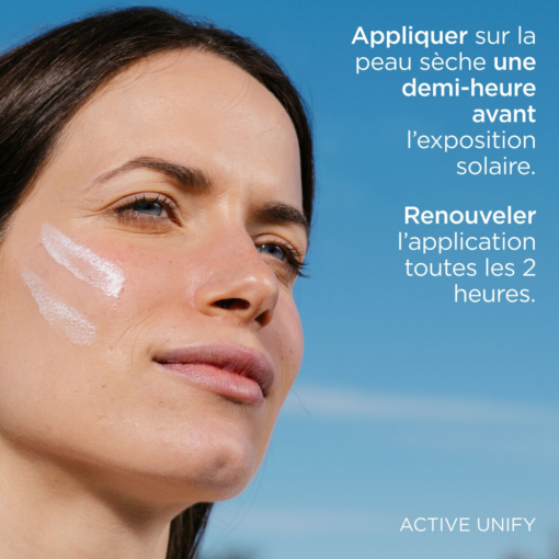 Femme appliquant la crème solaire Active Unify sur son visage.