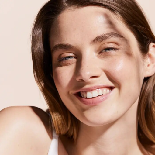 Femme souriante avec une peau lumineuse après application de la crème solaire Avène